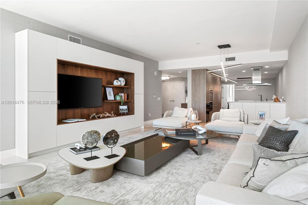 Living Room / Open Layout – The living room flows effortlessly toward the kitchen, with a custom media wall, built-in shelving, and contemporary lighting. The open-concept design enhances connection between the main gathering spaces.