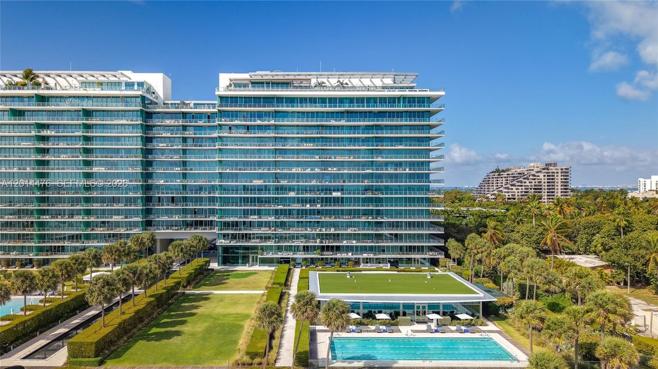 Exterior Building View – A full exterior view showcases the building’s contemporary glass façade, landscaped common areas, and nearby lap pool. The surrounding tropical greenery adds to the property’s polished resort-style setting.