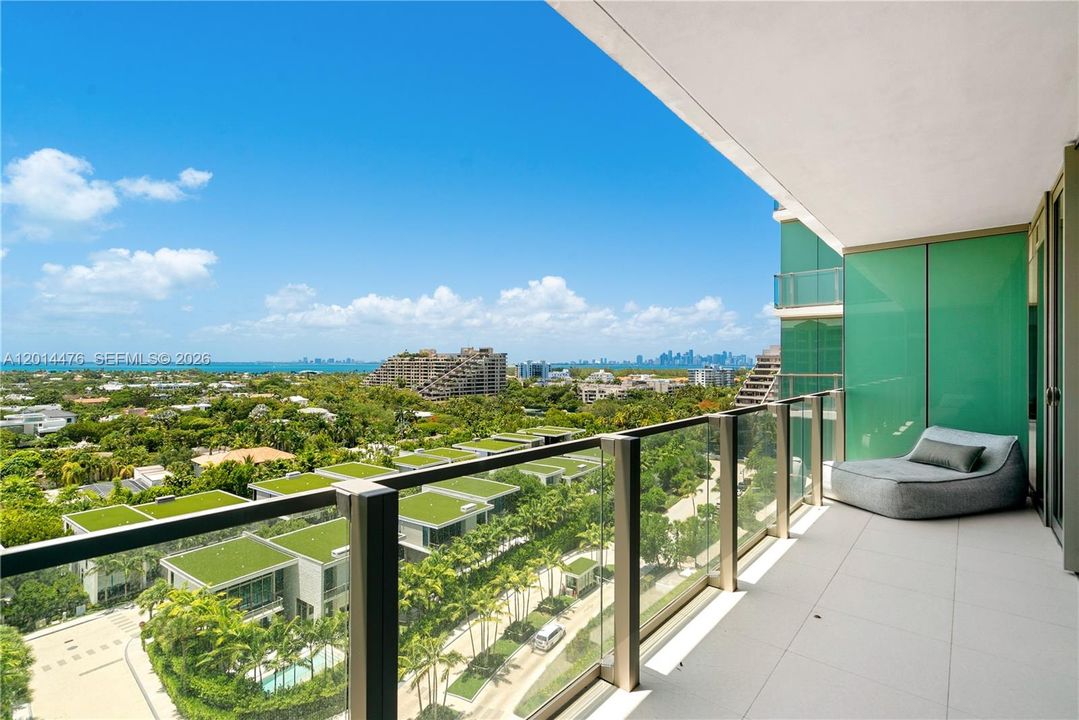 Private Balcony – The spacious balcony offers glass railings, a lounge area, and expansive views across lush greenery, surrounding residences, and the distant skyline. This outdoor setting extends the living space with an impressive open-air backdrop.