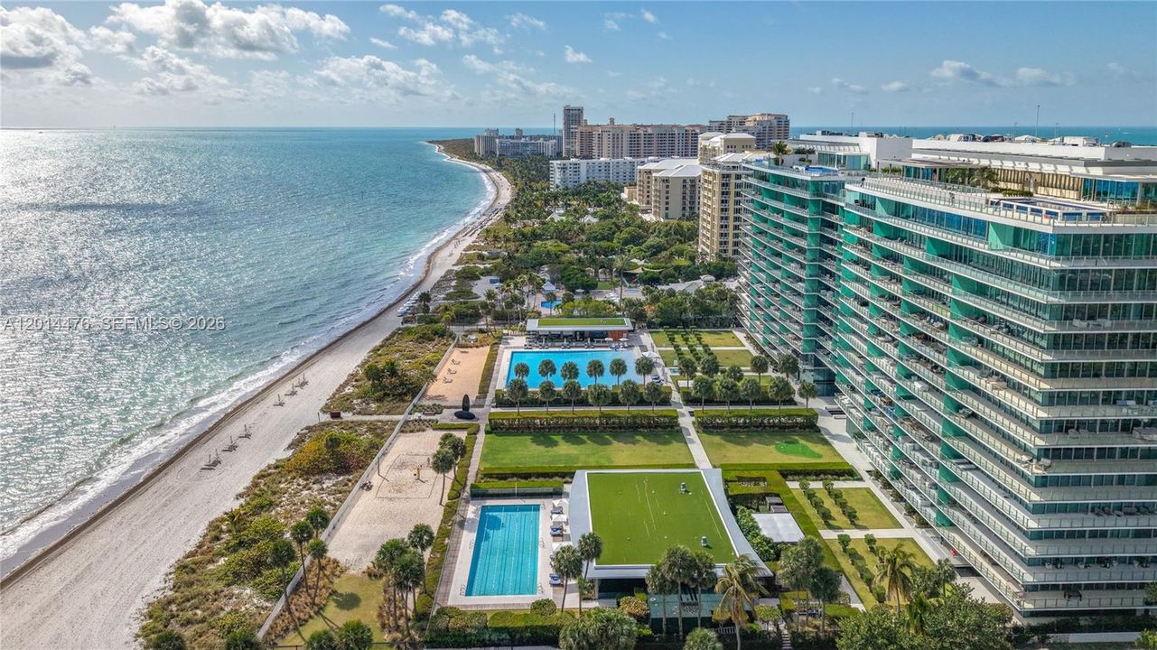 Aerial Coastline View – This aerial perspective highlights the building’s placement along the shoreline, with beach access, pools, and landscaped amenity areas visible below. The coastline stretches into the distance for a dramatic waterfront backdrop.