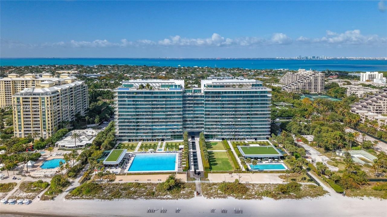 Full Exterior / Beachfront Overview – A broad exterior view presents the full building, landscaped grounds, resort-style pools, and direct beachfront frontage. The composition offers a complete look at the property’s oceanfront setting and amenity-rich surroundings.