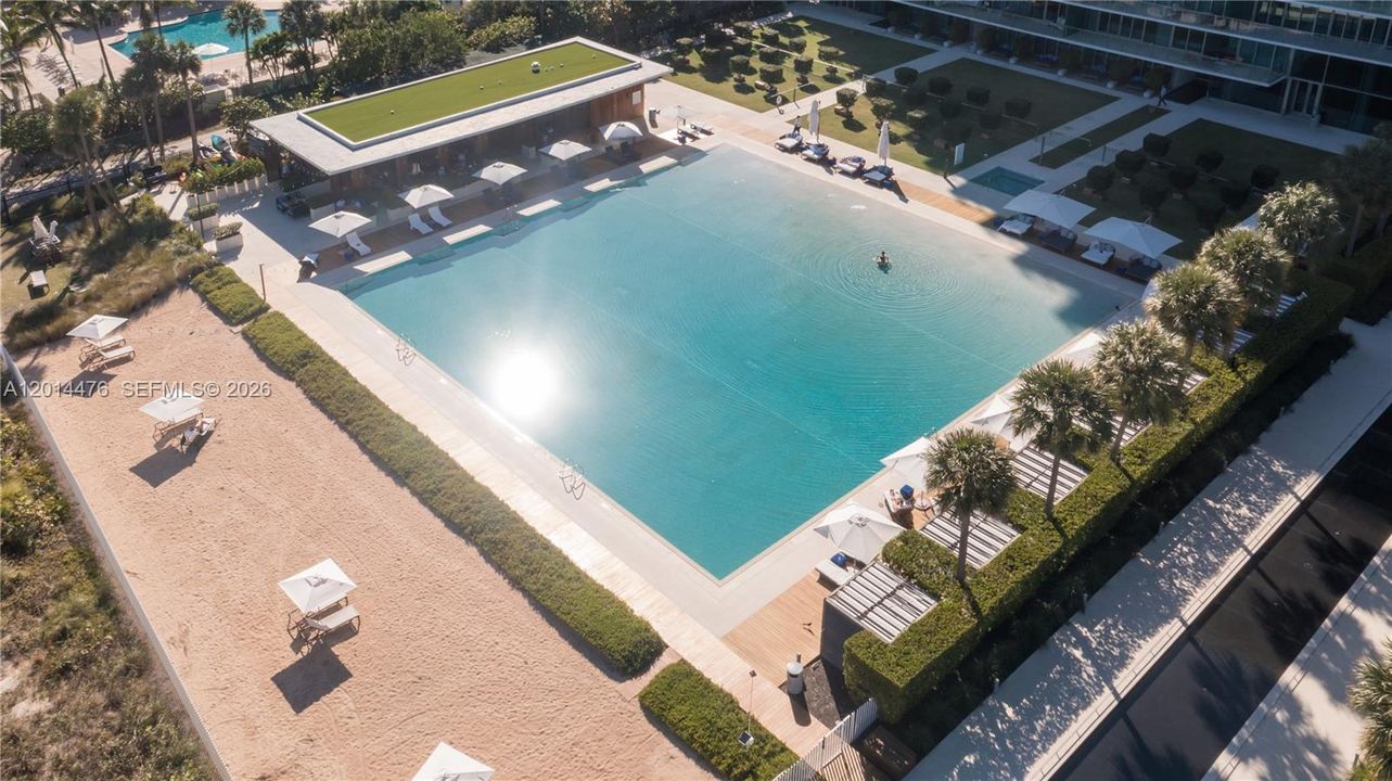 Aerial Pool and Beach View – The main pool deck is framed by cabanas, lounge areas, palms, and the nearby beach. The overhead view highlights the resort-style outdoor setting just steps from the sand.