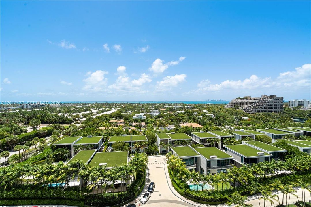 View – Panoramic views stretch over tropical landscaping, nearby residences, and sparkling water in the distance. The elevated perspective captures the property’s coastal setting and surrounding greenery.