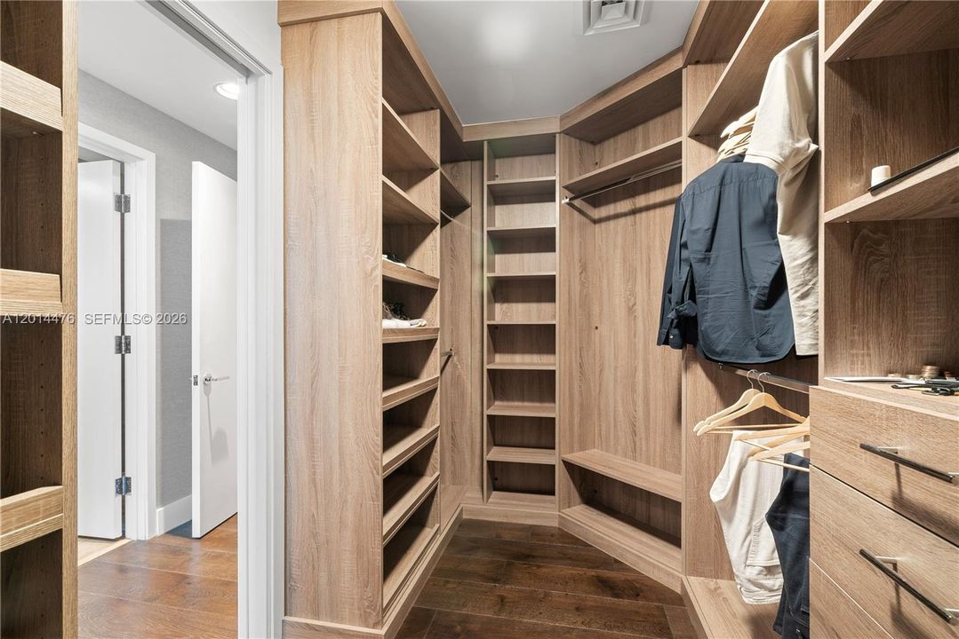 Walk-In Closet – The custom walk-in closet is designed with extensive open shelving, hanging areas, drawers, and built-in storage. Wood finishes and a generous layout create a polished, boutique-style organization space.