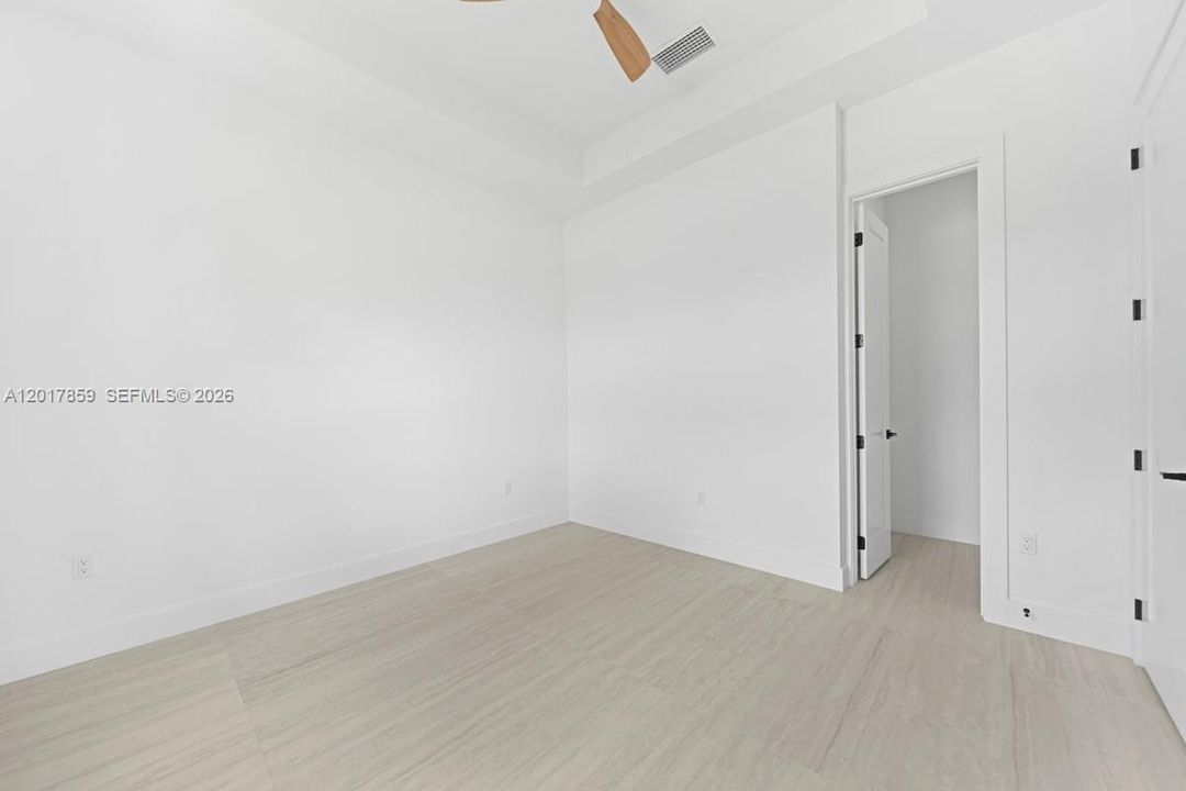 Interior space featuring a tray ceiling, wood-finish flooring, and a ceiling fan with wooden blades