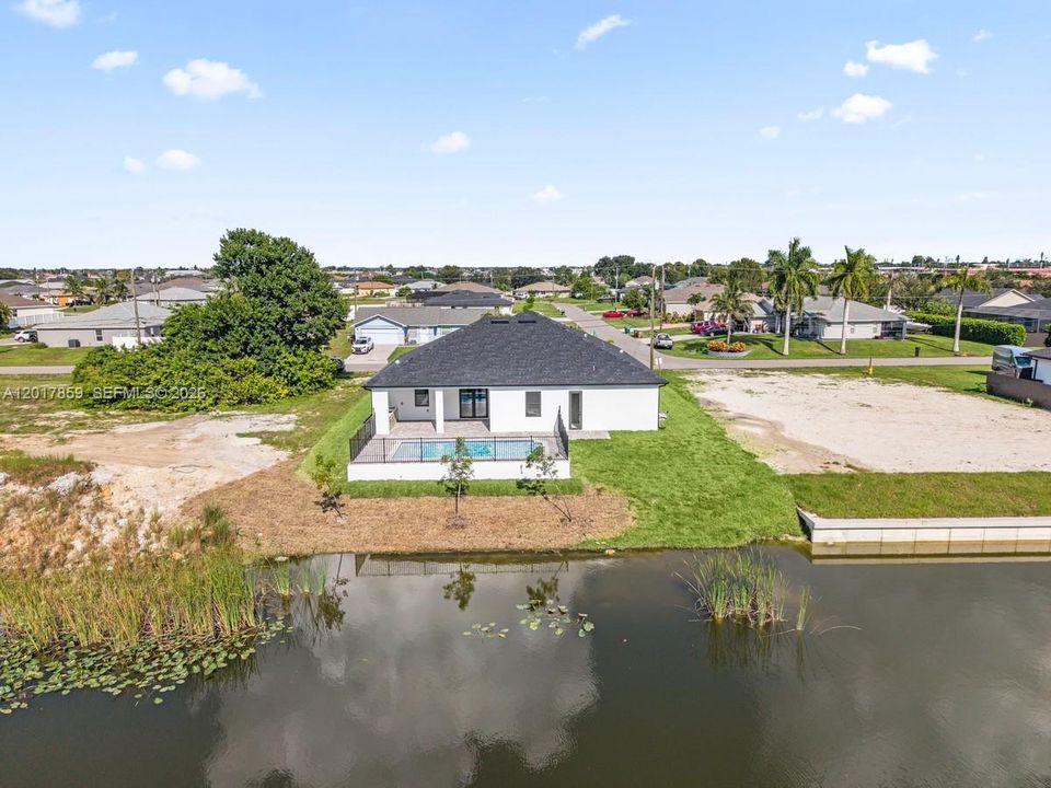 Waterfront residence featuring a private pool, screened-in enclosure, covered patio, and shingle roof