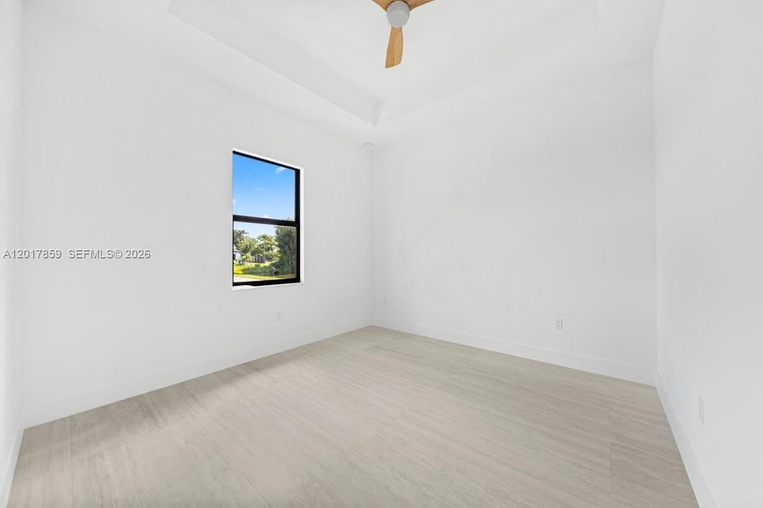 Room featuring a tray ceiling, wood-finish flooring, and a ceiling fan with light fixture