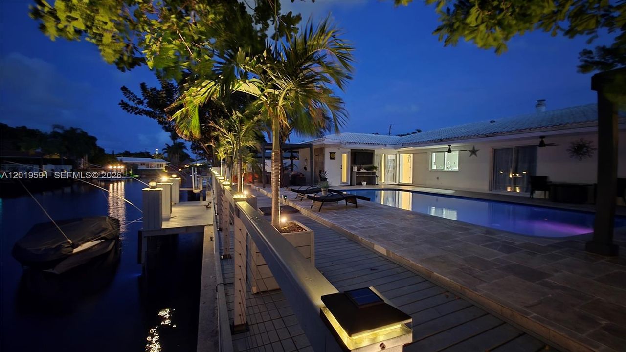 Stunning nighttime pool view with tropical lighting, private waterfront setting, and luxury outdoor living.