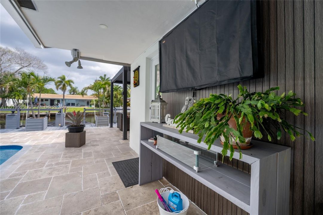Modern outdoor entertainment area with mounted TV, lounge space, and seamless indoor-outdoor living.