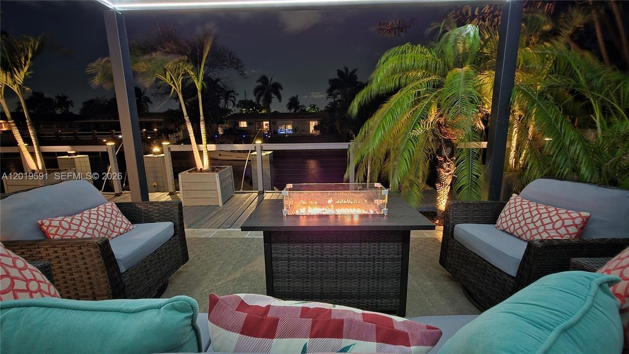 Luxury waterfront fire pit patio with ambient lighting and relaxing outdoor entertainment experience.