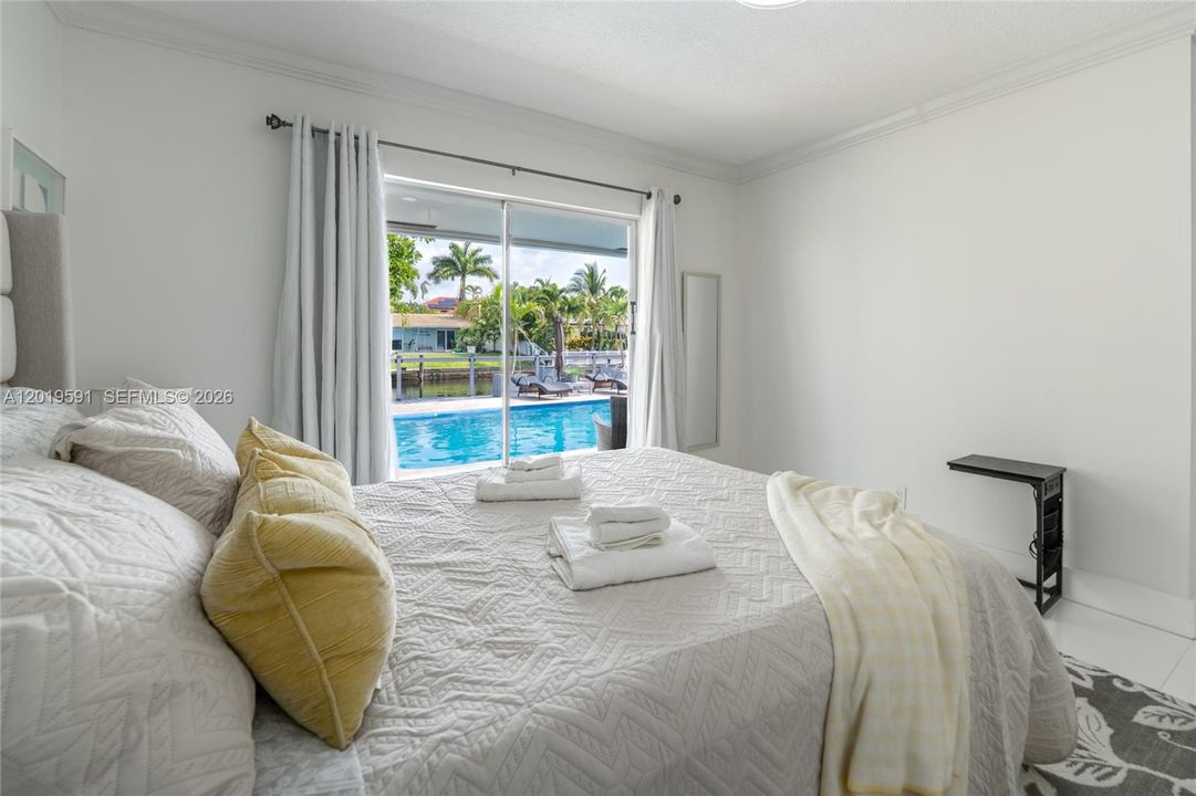 Bright pool-view bedroom featuring comfortable accommodations, modern styling, and tranquil natural light.