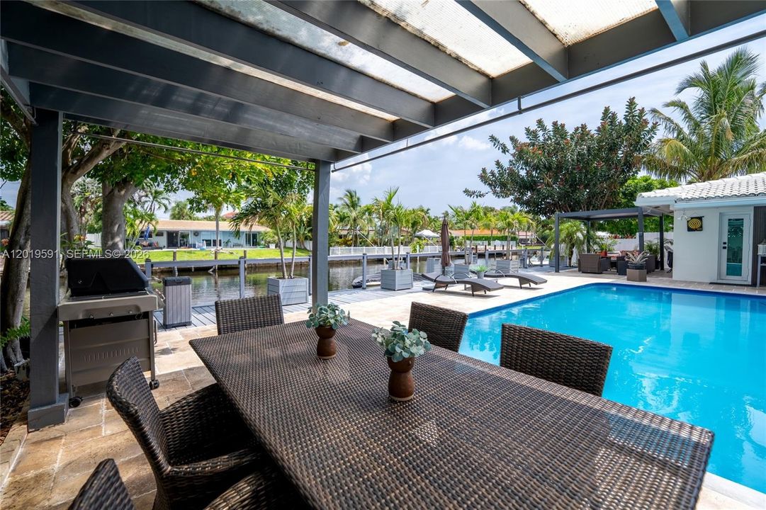 Covered waterfront outdoor lounge with heated pool views, tropical ambiance, and resort-style relaxation.