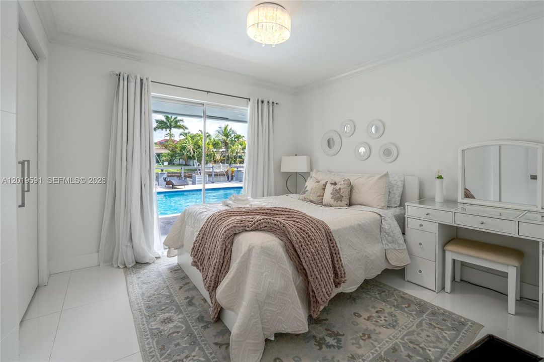 Stylish guest bedroom featuring cozy accommodations, poolside views, and bright contemporary design.