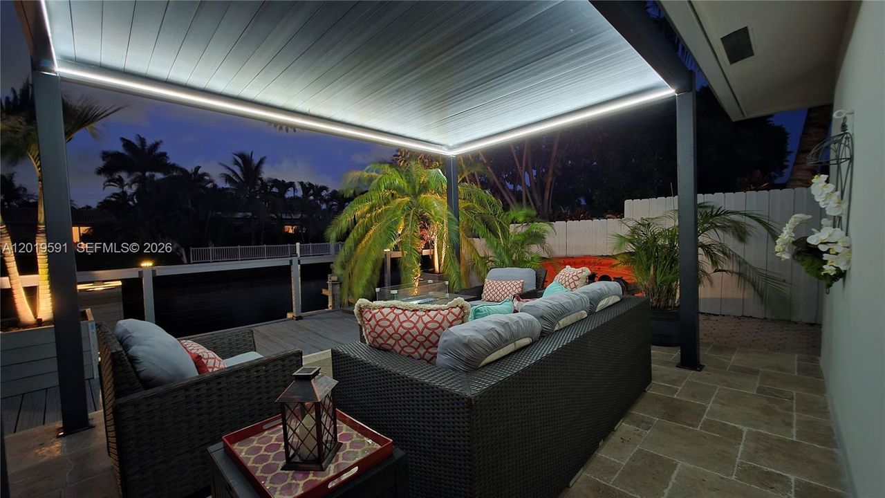 Covered outdoor lounge with LED lighting, waterfront views, and modern luxury evening atmosphere.