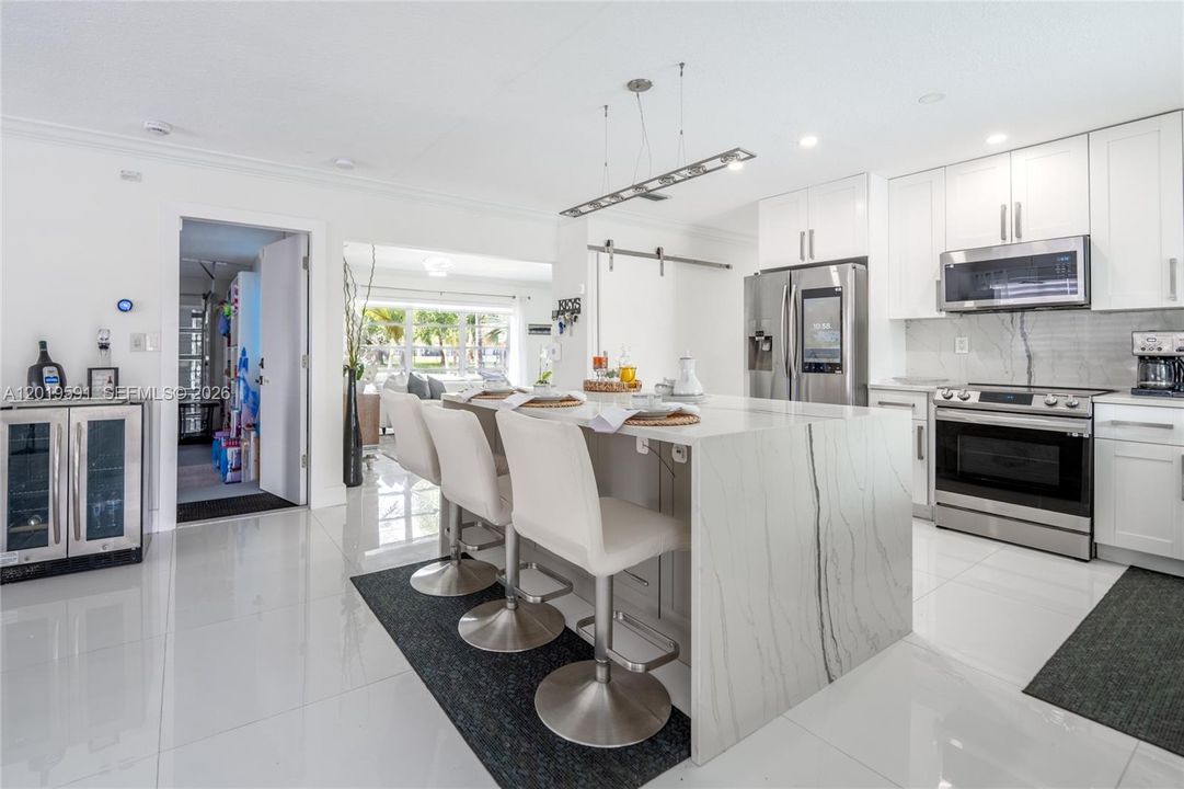 Elegant contemporary kitchen with bar seating, premium appliances, and stylish South Florida ambiance.