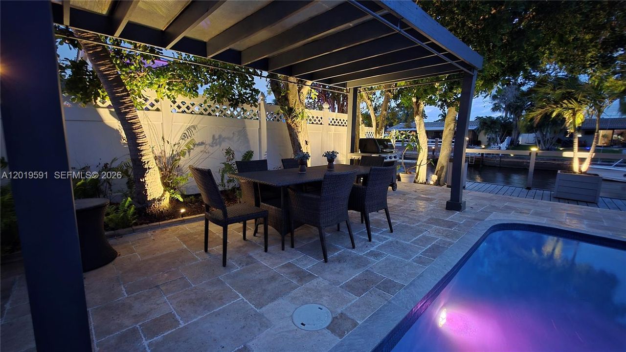 Luxury covered patio and pool area with ambient evening lighting and upscale waterfront entertaining space.