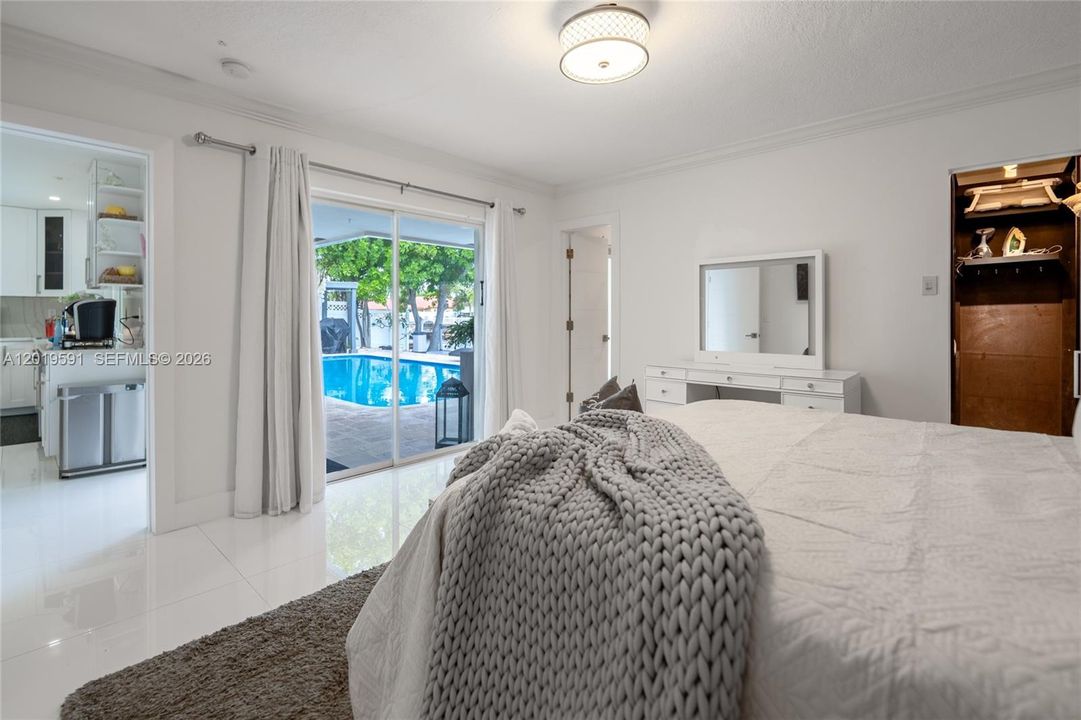 Bright waterfront bedroom with pool access views, natural light, and comfortable modern accommodations.