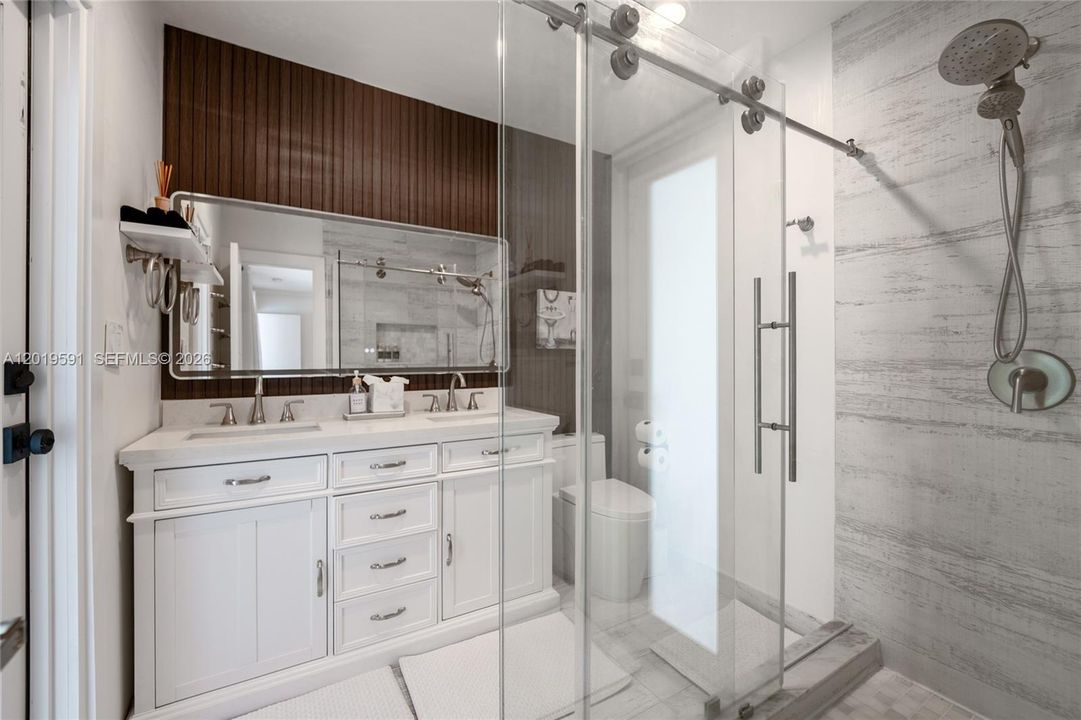 Modern spa-inspired bathroom with walk-in glass shower, double vanity, and upscale finishes.