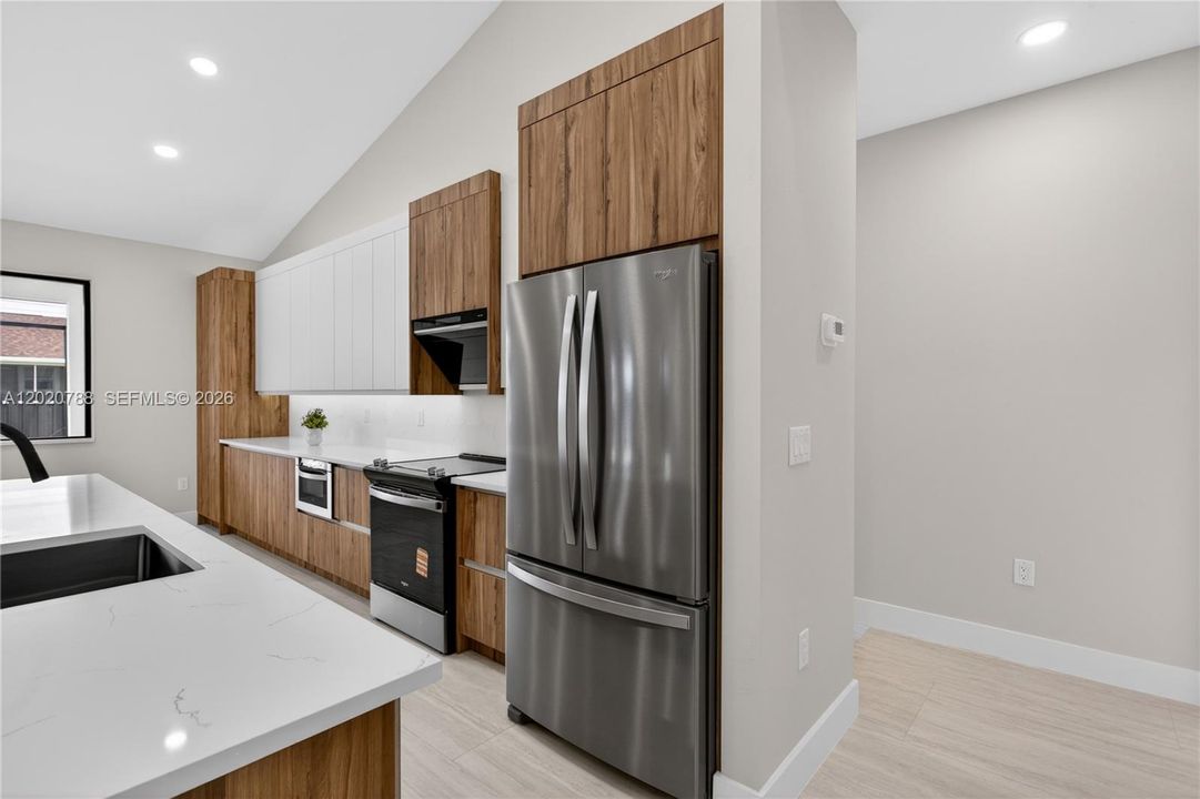 Crisp QUARTZ COUNTERTOPS & matching FULL BACKSPLASH complement modern palette, while UNDER-CABINET LED LIGHTING enhances the bright, open feel.