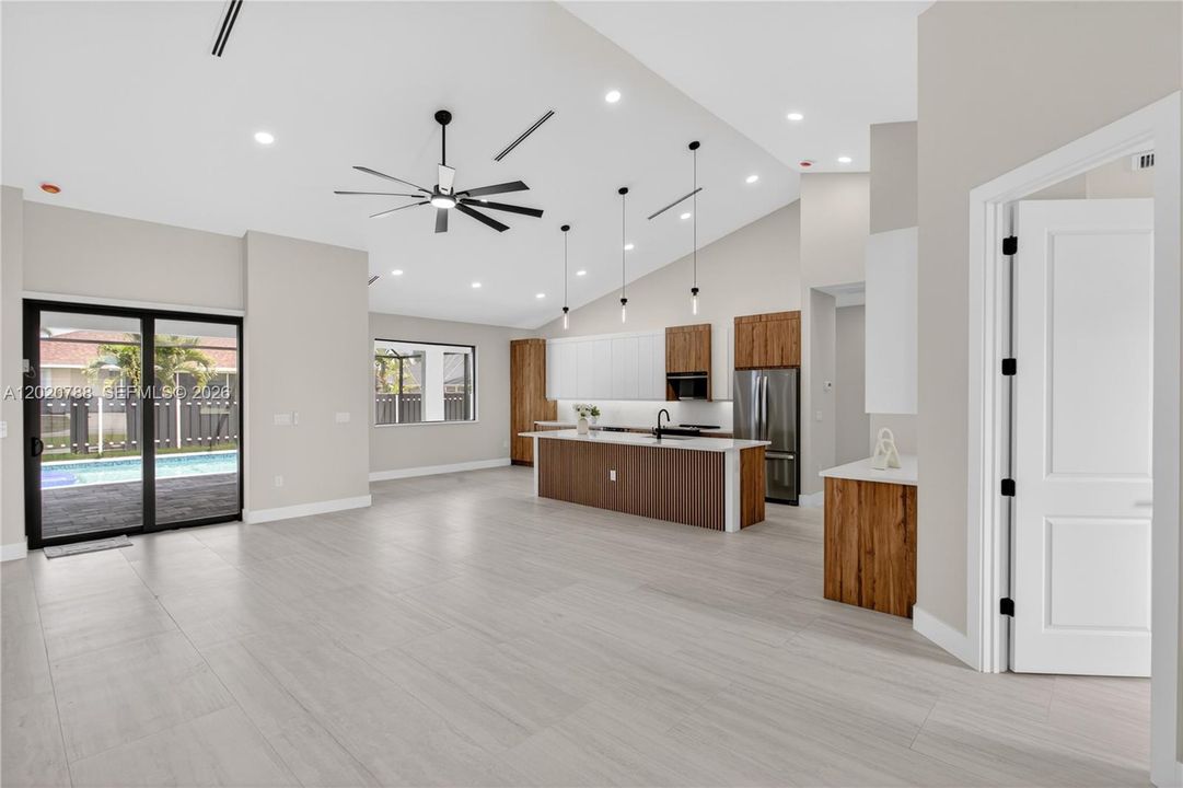 IMPACT-RESISTANT DOUBLE DOORS lead into WELCOMING LIVING ROOM w/ 12-ft VAULTED CEILING & SLIDING DOORS TO LANAI.