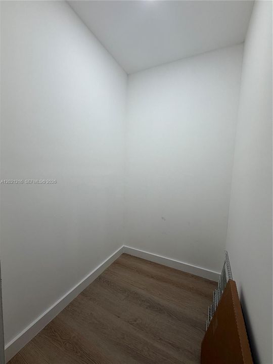 Enclosed space featuring neutral white wall finishes and wood-finish flooring