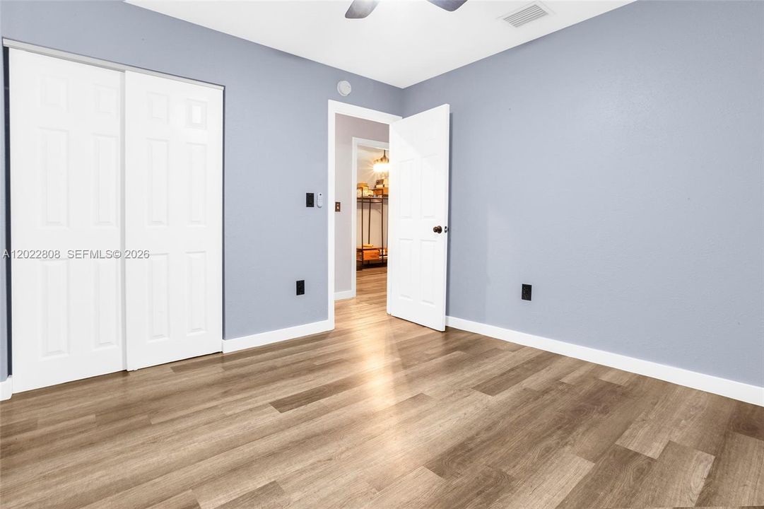 Secondary bedroom with modern flooring, natural light.
