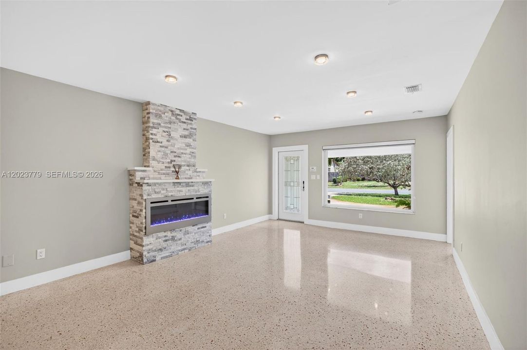 Stacked Stone Electric Fireplace with color changing light, lots of high hat lighting, beautiful restored polished terrazzo flooring. Flat ceilings and neutral beautiful paint