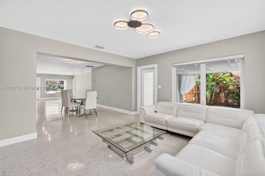 Inviting Family Room with Stacked Stone accent wall, original and restored and polished terrazzo floors and large impact windows overlooking the private tropical backyard
