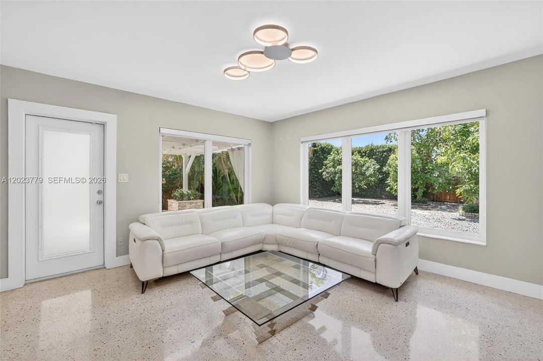 Inviting Family Room with Stacked Stone accent wall, original and restored and polished terrazzo floors and large impact windows overlooking the private tropical backyard