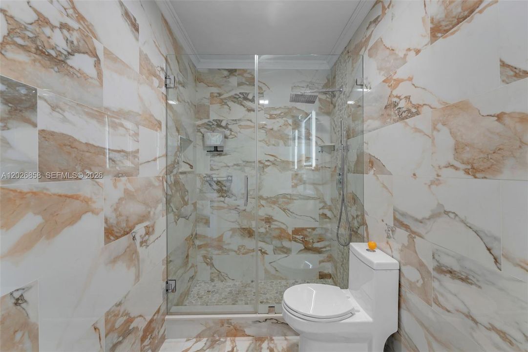 Elegant frameless glass shower with rainfall fixture and modern finishes throughout.
