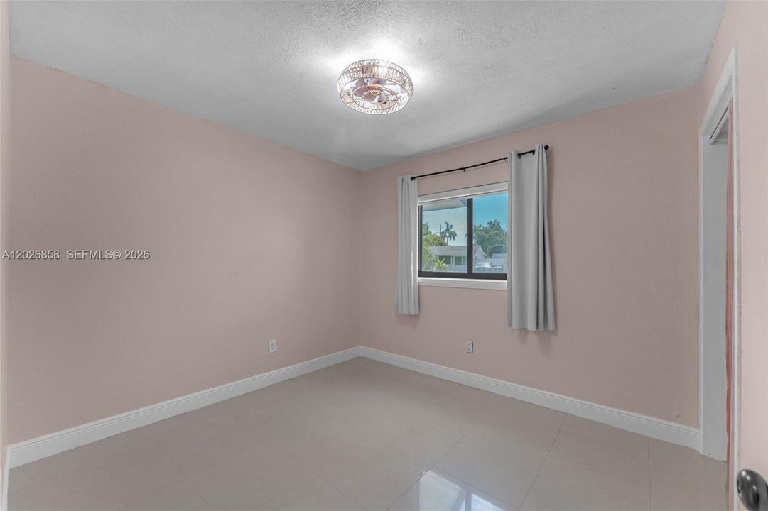 Spacious secondary bedroom with large window, tile flooring, and ample natural light.