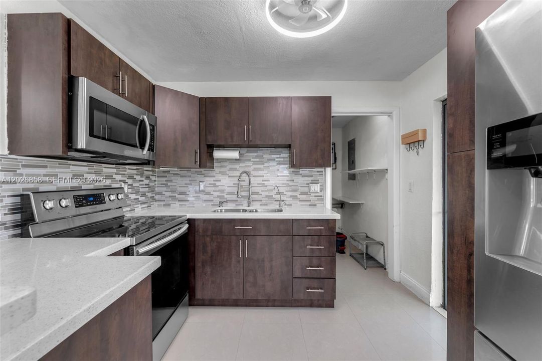 Beautifully renovated kitchen featuring quartz countertops, stainless steel appliances, and custom cabinetry.