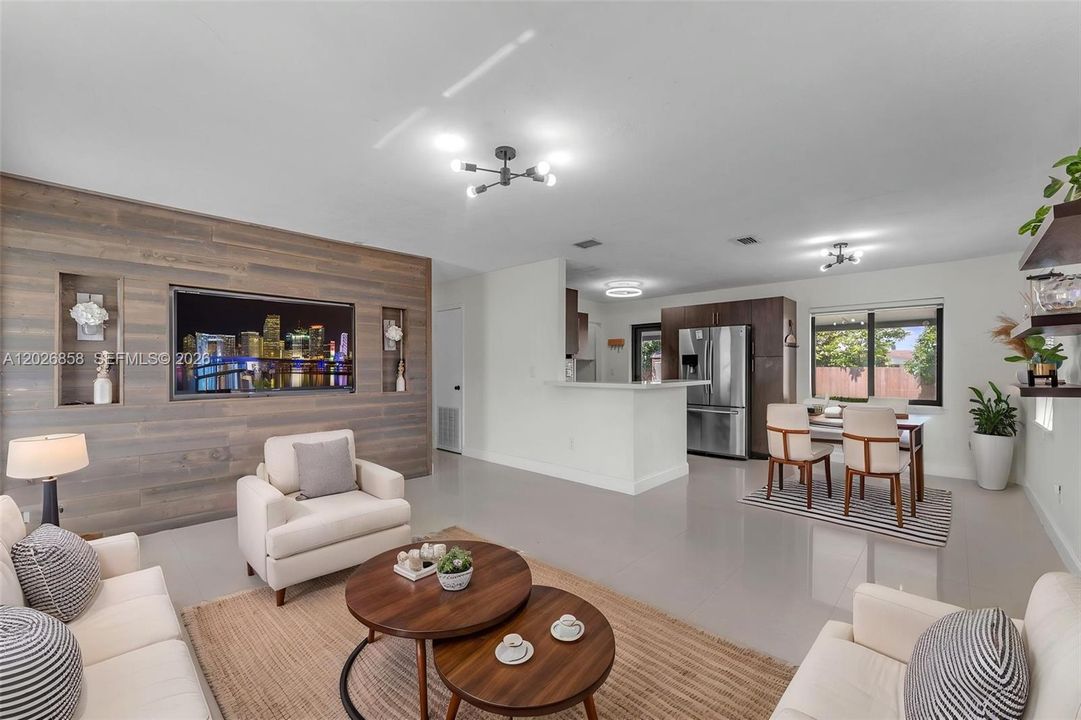 Open and airy living room with modern finishes, oversized tile flooring, custom accent wall, and seamless flow into the kitchen and dining area.