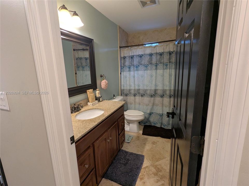 Second full bathroom featuring a granite-top vanity, modern lighting, and a clean tub/shower combo, offering a practical and well-maintained space for daily use.