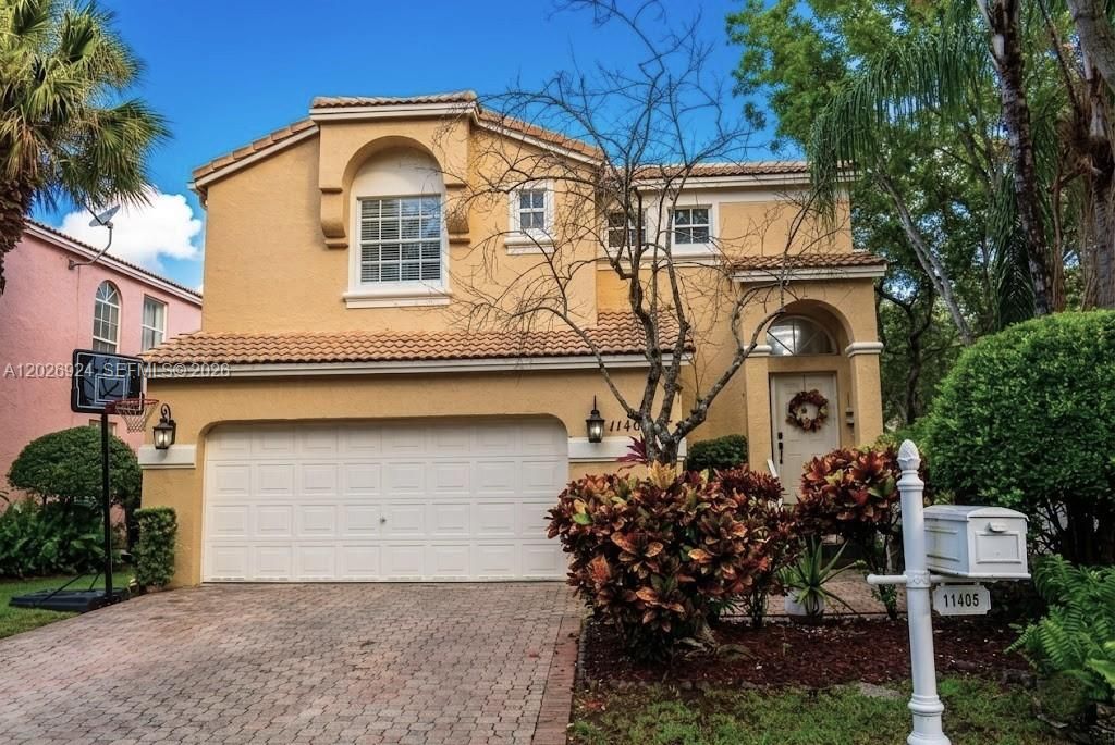 Sophisticated 3-bed, 2.5-bath residence offering 1,796 sq ft of refined living, highlighted by a brick-paved driveway, elegant Mediterranean architecture, and lush, manicured landscaping.