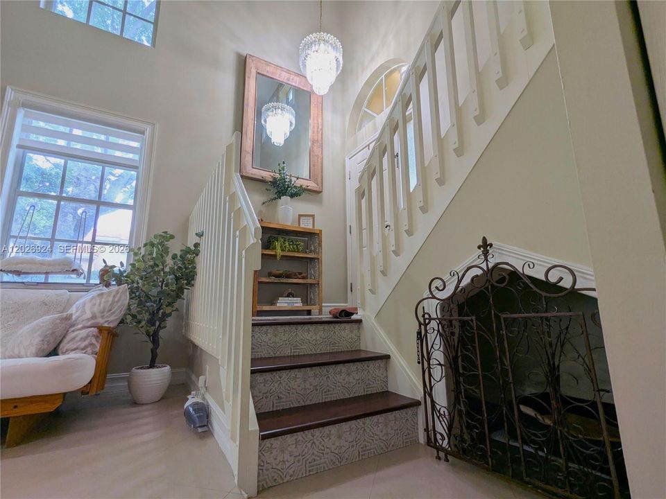 Charming staircase landing featuring decorative risers, accent wall, gorgeous chandelier, and warm natural light that enhances the home’s inviting character.