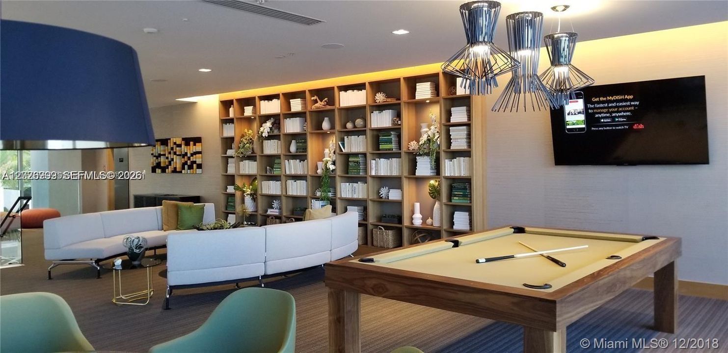 A stylish resident lounge includes a pool table, built-in shelving, comfortable seating, and modern lighting. The space is designed for relaxed gatherings and everyday enjoyment.