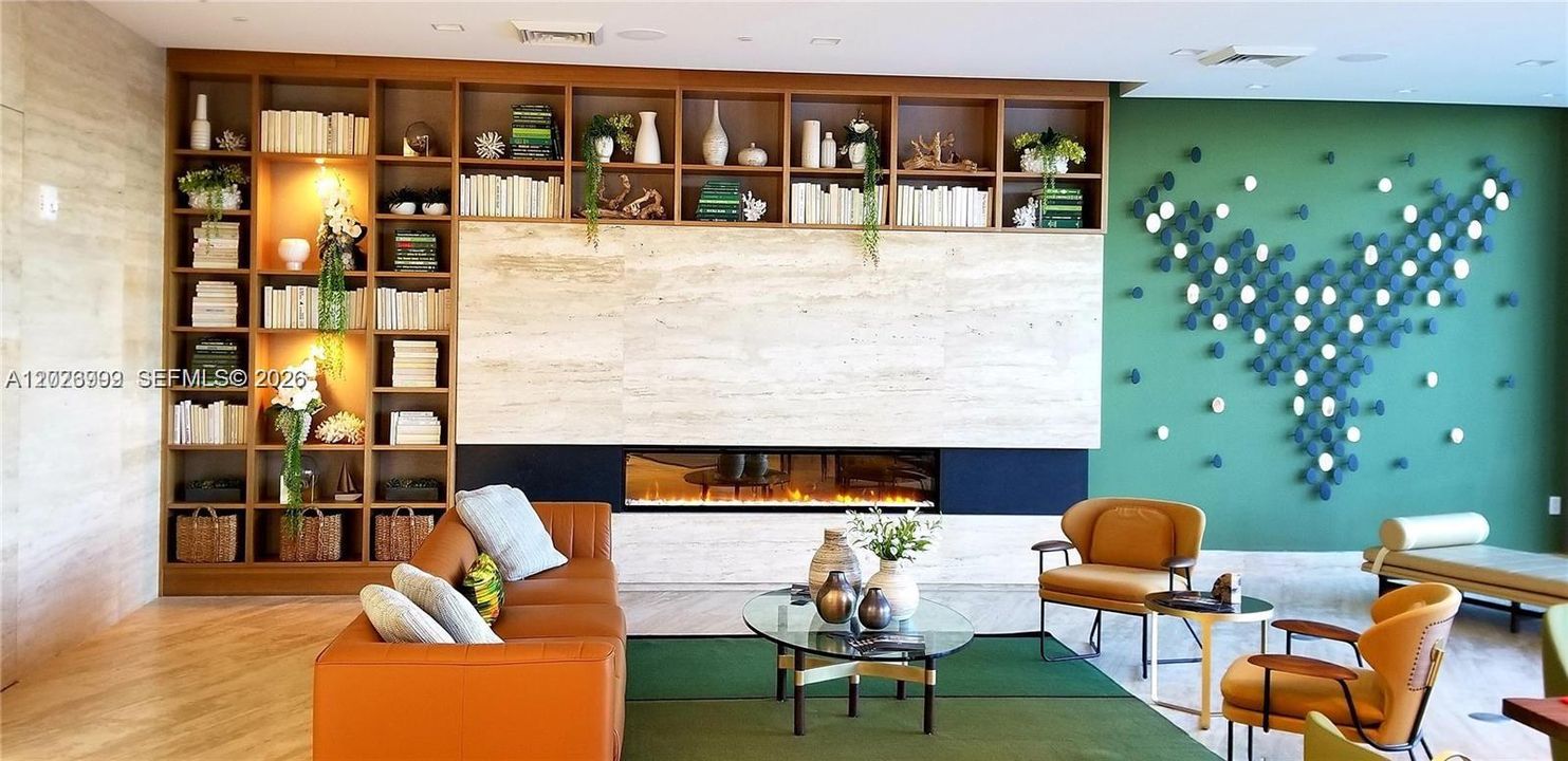 Warm wood built-ins, a linear fireplace, and contemporary seating create an inviting lounge area. Decorative wall accents and layered finishes give the space a refined, modern feel.