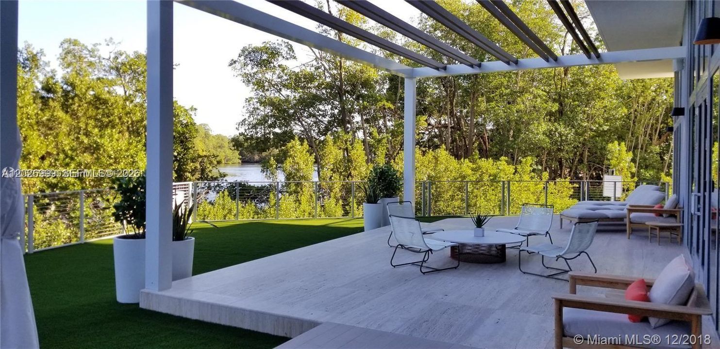 A serene outdoor seating area overlooks lush greenery and the waterway, creating a peaceful spot to unwind.