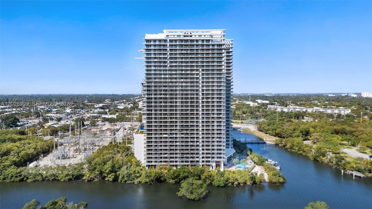A sleek modern tower rises along the water, offering a contemporary residential presence with expansive balcony lines.