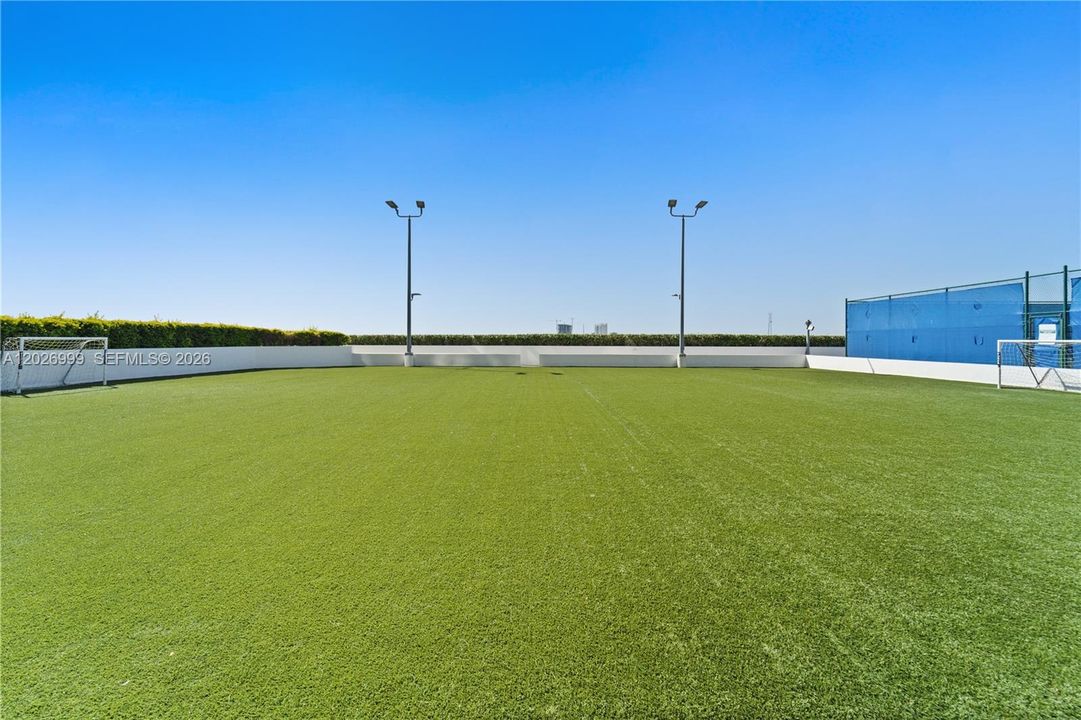 A dedicated outdoor soccer field with artificial turf offers a bright, open space for recreation and activity.
