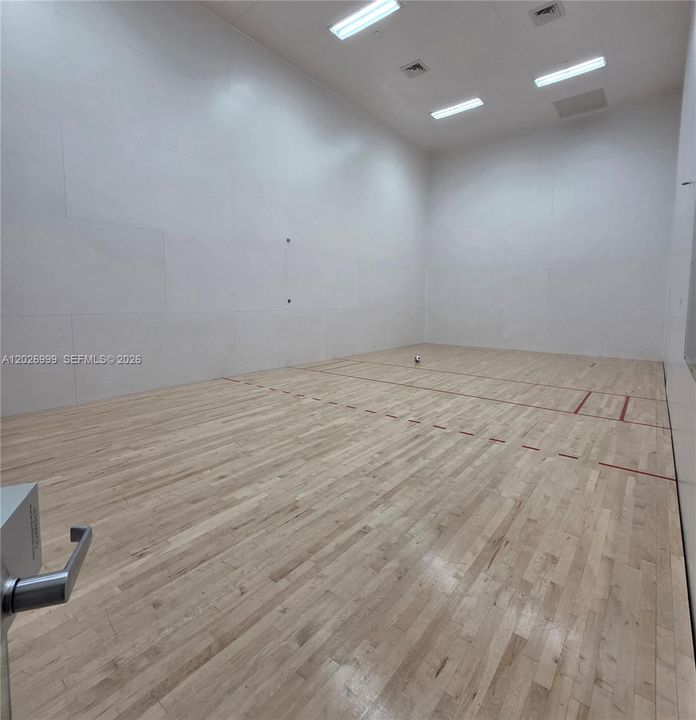 A professional-grade, glass-enclosed indoor court offers a versatile space for racquetball, handball, or other high-energy indoor activities.
