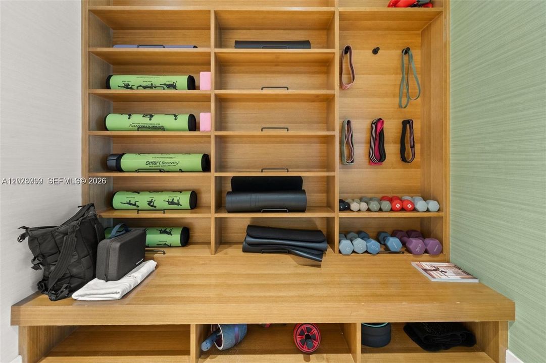 Organized wall system stocked with mats, dumbbells, and resistance bands for customized workouts.
