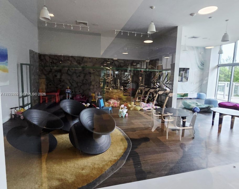 This vibrant, glass-enclosed playroom is filled with natural light and features a creative climbing wall and dedicated activity areas for children.