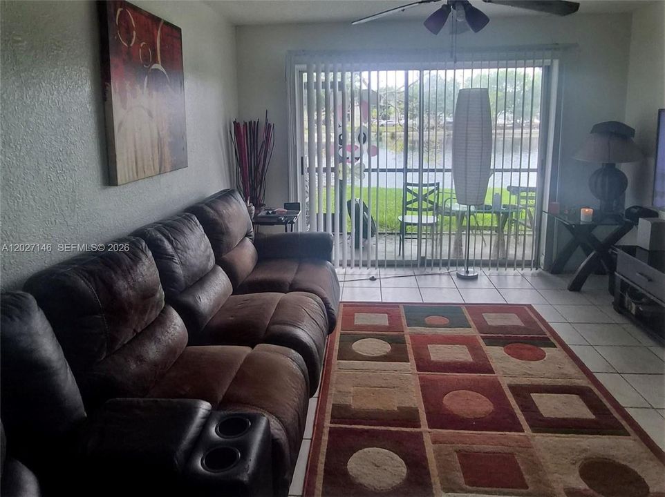 Light-filled, spacious living area featuring a large neutral tile layout, a comfortable sectional sofa setup, and massive sliding glass doors leading out to the patio.