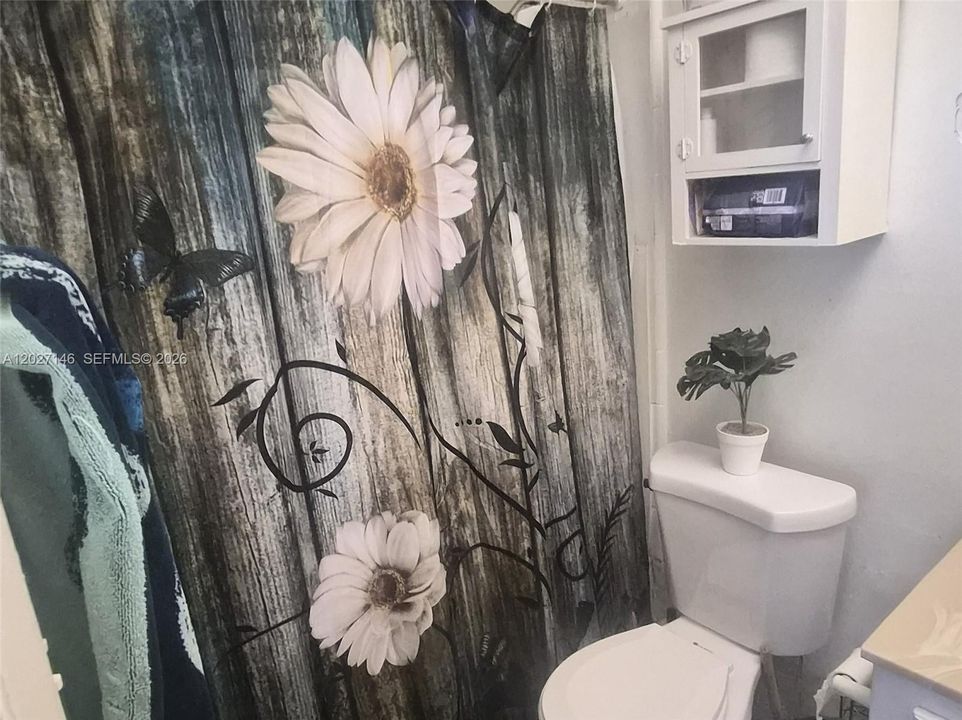 Full bathroom complete with a clean white vanity, large mirror, drop-ceiling tile design, and a full-size bathtub paired with a decorative shower curtain.