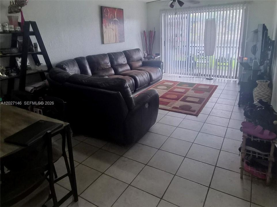 Light-filled, spacious living area featuring a large neutral tile layout, a comfortable sectional sofa setup, and massive sliding glass doors leading out to the patio.