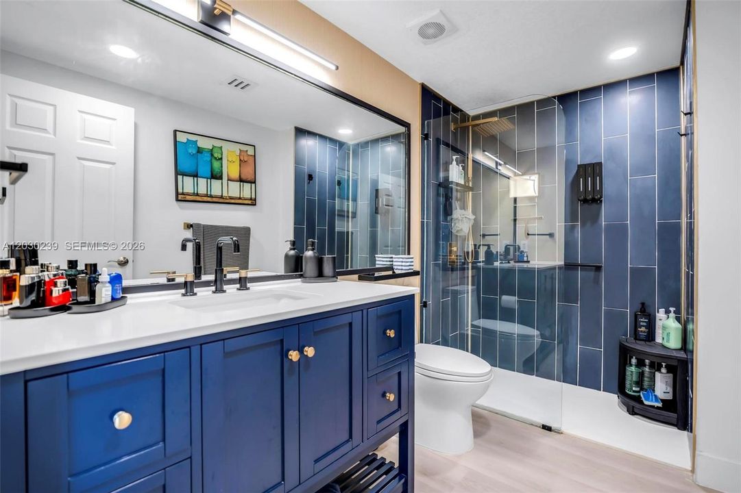 Beautifully remodeled modern bathroom featuring blue accents and a glass shower door.