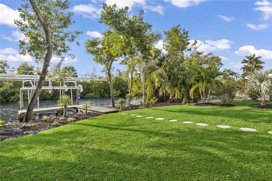 Mature palms, tropical landscaping, and lush greenery surround the property, creating exceptional wall privacy and a true backyard oasis