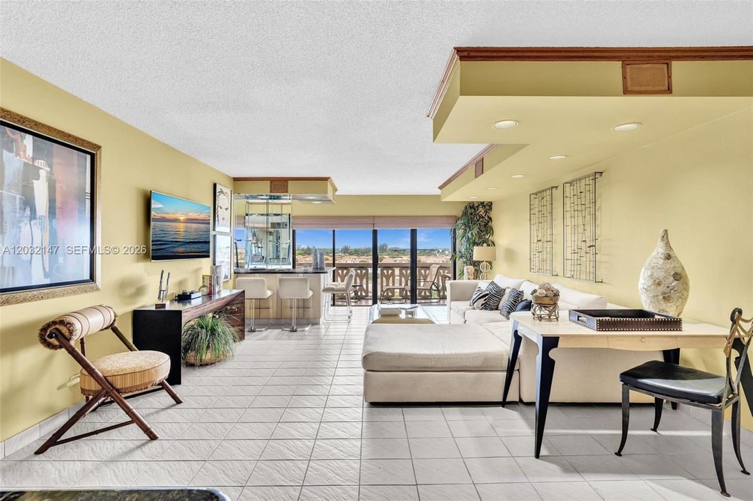 LARGE LIVING ROOM PERFECT FOR RELAXING OR ENTERTAINING! THE CUSTOM BAR OVERLOOKS THE STUNNING VIEW OF THE CANAL, POOL, AND BEAUTIFUL GREENERY. THIS UNIT COMES FULLY FURNISHED WITH CUSTOM DESIGNER FURNITURE.